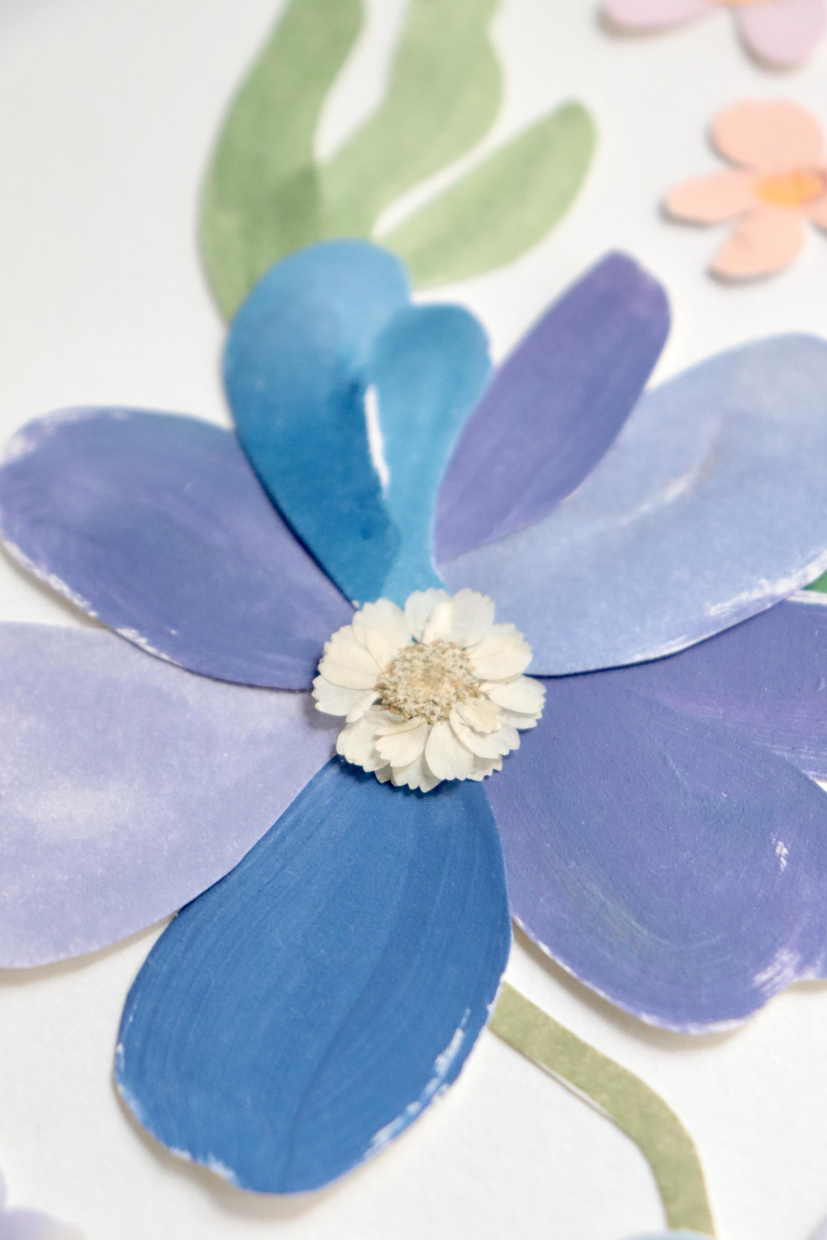 détails herbier original A4 nommé céleste, collage de fleurs en papier en relief et fleurs pressées sur fond blanc, encadré dans un cadre en bois bleu, création Chemin des Marettes.