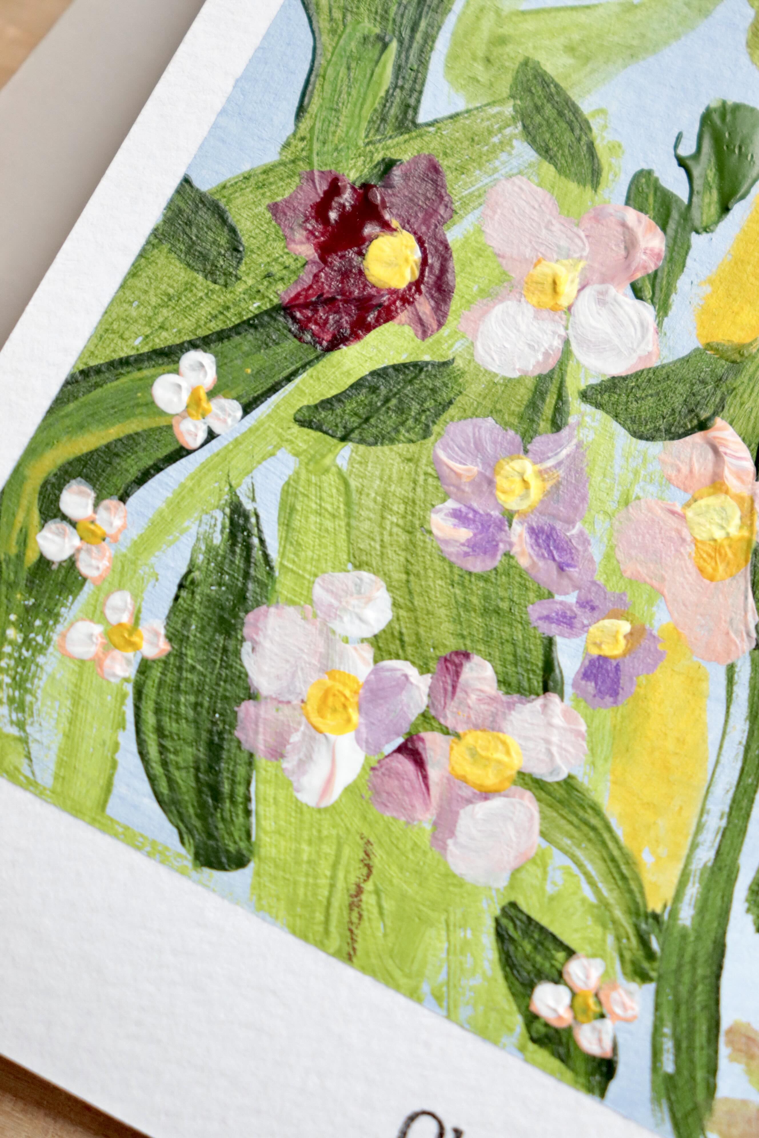 Mini peinture acrylique originale A5 nommée Rivage, par Chemin des Marettes. Fleurs blanches rouges et violettes et feuillage vert sur un fond bleu ciel doux. Style botanique aérien et poétique, idée cadeau pour la Fête des Mères.