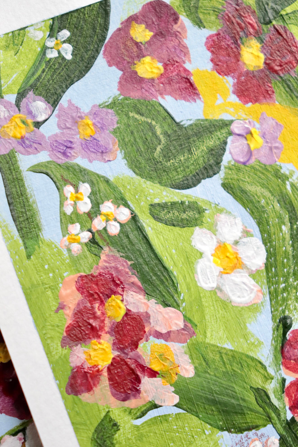 Mini peinture acrylique originale A5 nommée Rivage, par Chemin des Marettes. Fleurs blanches rouges et violettes et feuillage vert sur un fond bleu ciel doux. Style botanique aérien et poétique, idée cadeau pour la Fête des Mères.